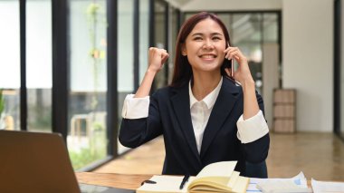 Heyecanlı genç bir çalışan cep telefonuyla konuşuyor, iyi haberler alıyor, harika haberler duymayı kutluyor..