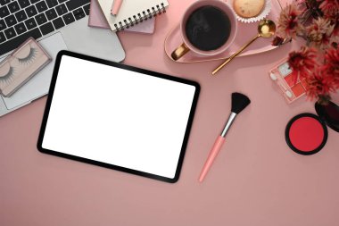 Düz tablet, makyaj fırçaları, kozmetik ürünleri ve pembe arka planda dizüstü bilgisayar.