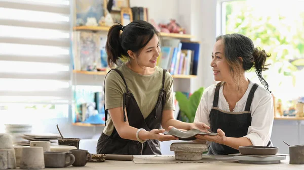 Smiling Mature Woman Potter Teaching Young Woman Sculpting Clay Dishes — 스톡 사진