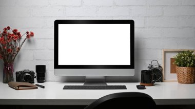 Creative workplace with computer pc, camera, notebook and houseplant on wooden desk. Empty display for your advertise text.