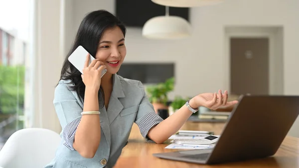 Asian Female Employee Having Pleasant Phone Conversation Using Laptop Office — 스톡 사진