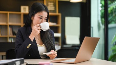 Kahve içen çekici bayan girişimci dizüstü bilgisayarda okuma bilgisi.
