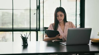 Modern ofis alanında dizüstü bilgisayarda çalışan odaklanmış genç bayan çalışan..