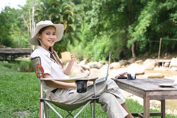 Woman traveler resting in folding chair near the river bank. Adventure, travel, tourism and camping concept.