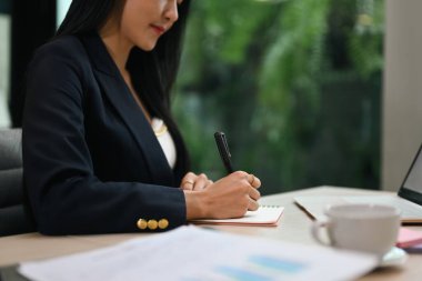 Profesyonel milenyum iş kadını işyerinde oturuyor ve belgeyi imzalıyor..
