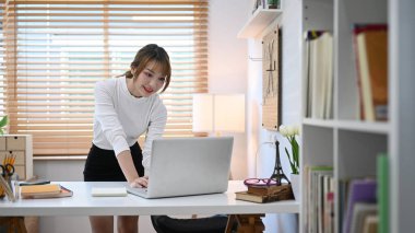 Pretty young female freelancer woman typing mails answers, working online on laptop at home office.