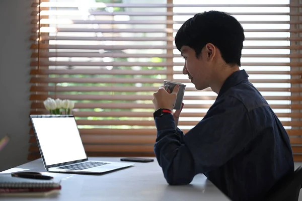 Side View Asian Male Entrepreneur Drinking Coffee Reading Email Laptop — ストック写真