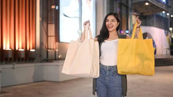 Cheerful Asian Woman Carrying Shopping Bags Walking City Street Evening — Stok fotoğraf