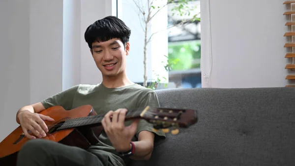 Relaxed Young Asian Man Playing Acoustic Guitar Couch Enjoying Carefree — Stockfoto