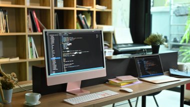 Yazılım geliştirme şirketindeki ekranlarda programlama kodu olan bilgisayar bilgisayarı ve dizüstü bilgisayar.