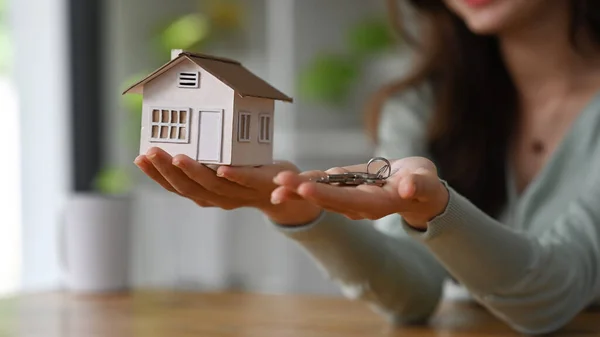 Cropped imaged of real estate agent hands holding house model and keys. Real estate investment, purchase and sale concept.