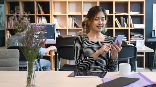 Smiling Asian Female Employee Sitting Working Space Using Smart Phone — Φωτογραφία Αρχείου