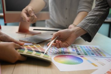 Graphic designers team working with color swatches and brainstorming for new project at creative office.