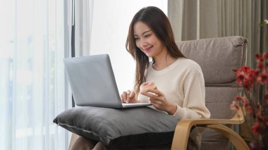 Young woman checking email or surfing internet on laptop in cozy winter or autumn weekend.