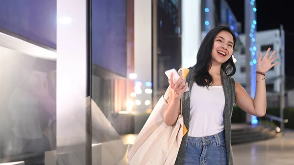 Trendy Young Woman Greeting Someone While Walking Night City Streets — Stok fotoğraf