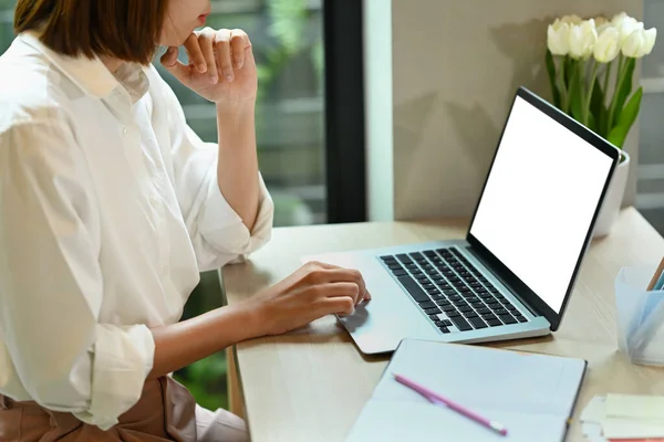 Female freelancer working online, reading online information on her laptop computer.