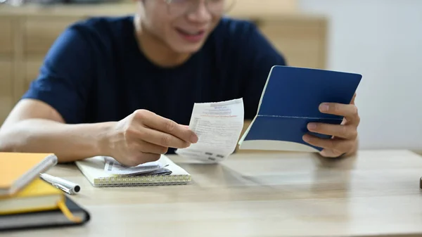 Young man holding paper bills using calculator for calculating money bank loan rent payments, managing expenses finances.