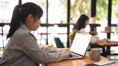 Side view young employee searching online information, working with laptop at corporate office.