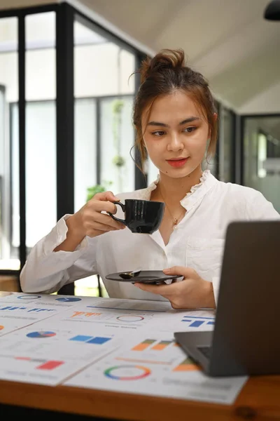 Shot Attractive Young Businesswoman Drinking Coffee Using Laptop Her Workstation — 스톡 사진