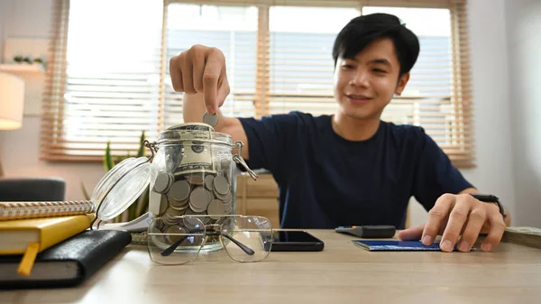 Smiling Young Asian Male Putting Coin Jar Money Future Retirement — 图库照片