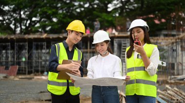 Engineers team wearing safety helmet and vest inspecting industrial building construction site. Industry, Engineer, construction concept.