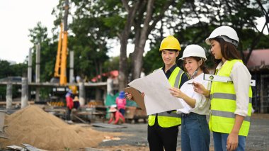 Engineers team wearing safety helmet and vest inspecting industrial building construction site. Industry, Engineer, construction concept.