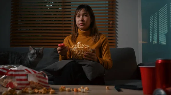 Young Woman Holding Remote Control Eating Popcorn While Watching Home — 스톡 사진