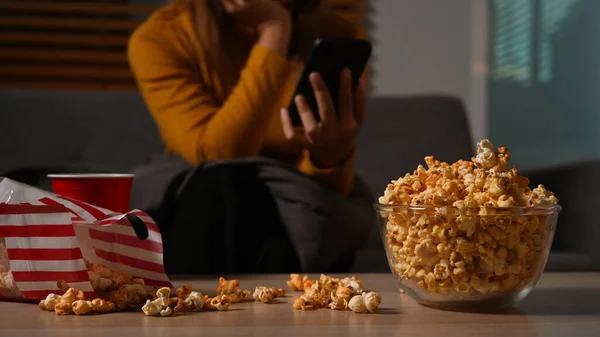 Woman Using Mobile Phone Eating Popcorn While Sitting Dark Living — Stockfoto