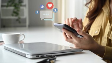 Close up view of woman hands holding and typing on smart phone with notification icons of like, message and comment.