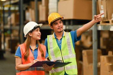 Warehouse managers and worker walking through retail warehouse full of shelves and checking supply export shipment.