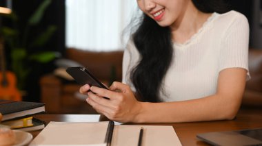 Smiling young woman using mobile phone for chatting with friends. Technology, social network, communication concept.