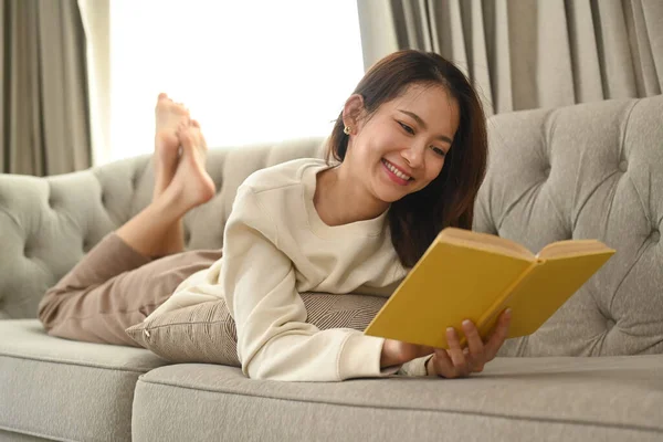 Smiling Young Woman Lying Couch Reading Book Enjoy Stress Free — 图库照片
