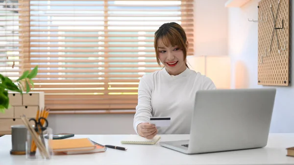 Pretty woman with credit card and purchasing product via online shopping on laptop. Online shopping, internet banking concept.