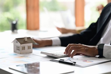Businessman investors hand using calculator for calculating loan of finance and planning for real estate investment.