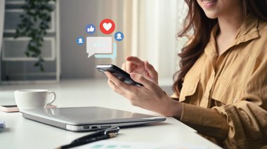 Young woman hands holding and typing on smart phone with notification icons of like, message and comment.