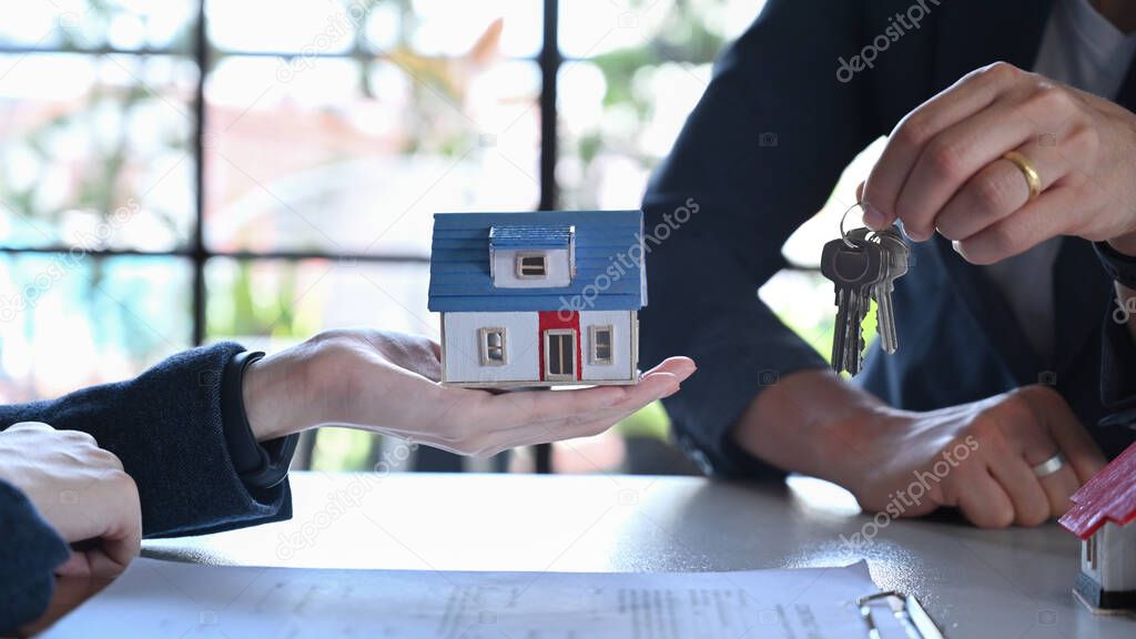 Real estate agent giving keys of new house to customer. Property purchase, mortgage and loan ownership concept.