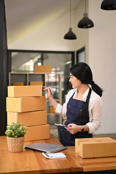 Small business entrepreneur preparing parcel boxes of product for delivery to costumer. Online selling, e-commerce concept.