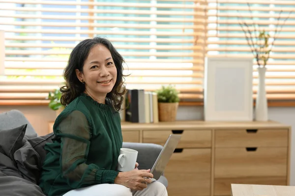 Satisfied Middle Aged Woman Sitting Bright Living Room Using Laptop — 스톡 사진