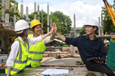 Architect team and engineers are making high five together. Industry, Engineer, construction concept.