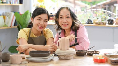Happy young woman and middle aged woman creating handicraft crockery in workshop. Activity, handicraft, hobbies concept.