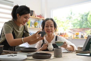 Happy young woman and middle aged woman creating handicraft crockery in workshop. Activity, handicraft, hobbies concept.