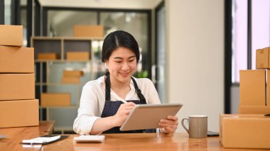 Young woman entrepreneur working in home office, preparing parcel boxes of product for delivery. Online selling, e-commerce concept.