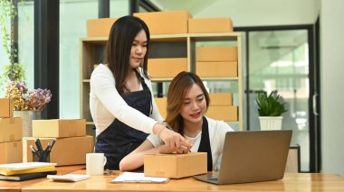 Young woman entrepreneur working in home office, preparing parcel boxes of product for delivery. Online selling, e-commerce concept.