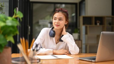 Thoughtful woman freelancer sitting at her home office and looking out of window, dreaming about future or new successful projects.