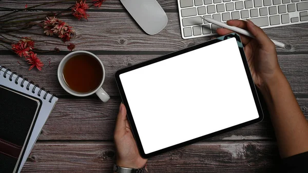 Top view digital tablet with empty display, notebook and supplies on wooden office desk.