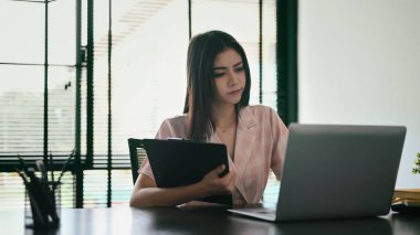 Concentrated female manager using laptop, preparing reports for corporate meeting.