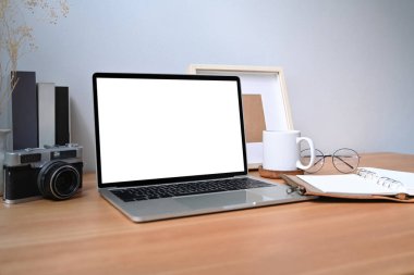 Beyaz ekranlı bilgisayar, kahve fincanı ve ahşap masadaki kitaplar..