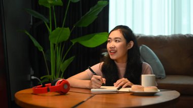 Pretty Asian woman doing homework, learning online on laptop at home. E-learning education concept.