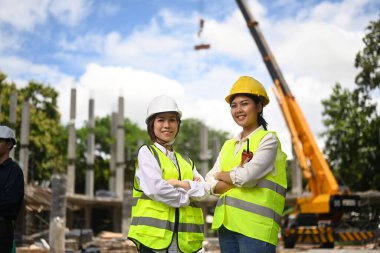 Female architects standing with arms crossed at construction site. Industry, Engineer, construction concept.