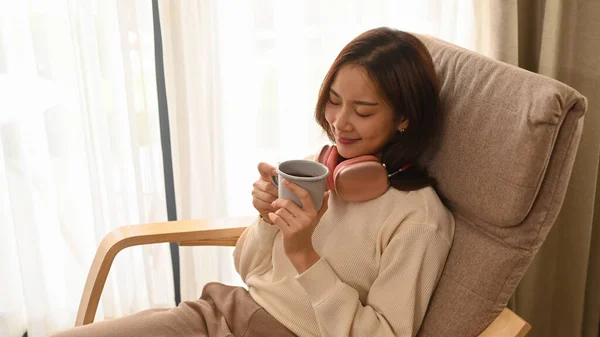 Peaceful woman in warm sweater drinking hot chocolate, enjoy stress free peaceful mood at home in sunny winter day.